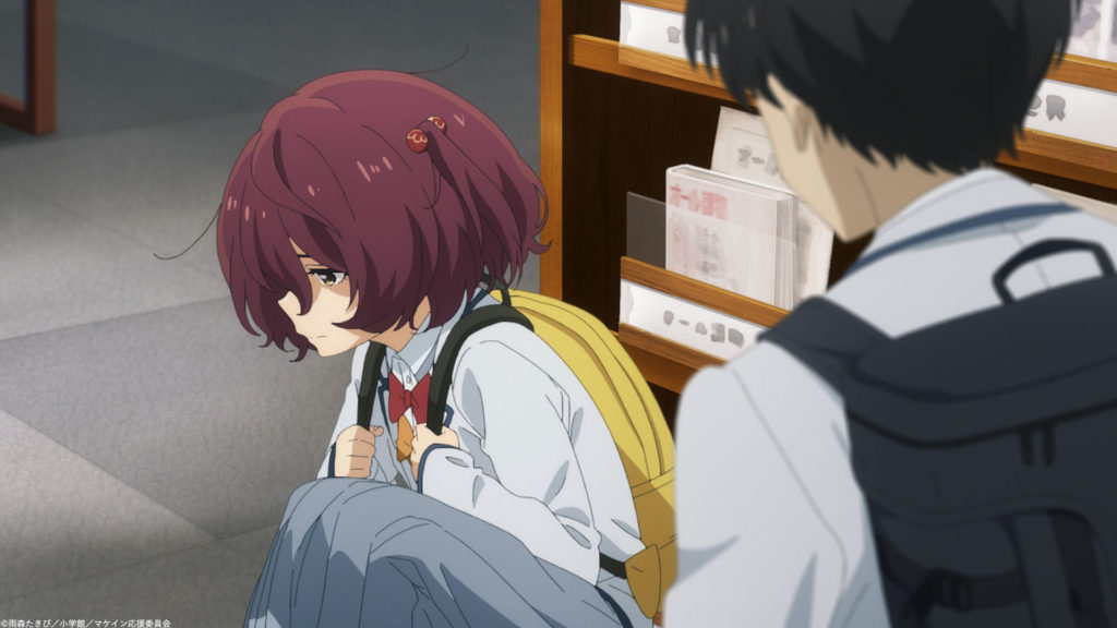 Komari, a timid girl with red hair, crouched in front of a bookshelf looking away from Nukumizu, a teen boy